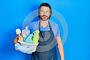 Middle age caucasian man holding cleaning products thinking attitude and sober expression looking self confident