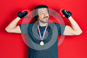 Middle age caucasian man wearing first place medal on boxing competition smiling looking to the side and staring away thinking