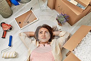 Middle age caucasian woman relaxed lying on the floor at new home