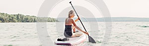 Middle age Caucasian woman riding paddle sup surfboard. Female doing individual sport active workout