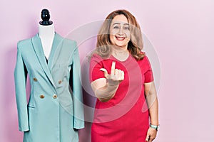 Middle age caucasian woman standing by manikin beckoning come here gesture with hand inviting welcoming happy and smiling