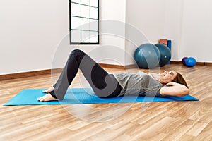 Middle age caucasian woman training abs exercise at sport center