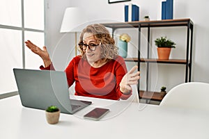 Middle age caucasian woman using laptop sitting on the table at home celebrating victory with happy smile and winner expression