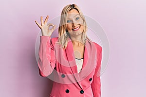 Middle age caucasian woman wearing business jacket smiling positive doing ok sign with hand and fingers
