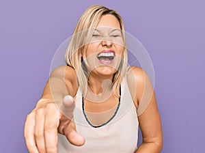 Middle age caucasian woman wearing casual clothes laughing at you, pointing finger to the camera with hand over body, shame