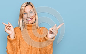 Middle age caucasian woman wearing casual winter sweater smiling confident pointing with fingers to different directions