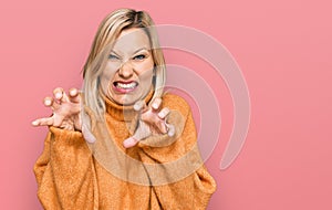 Middle age caucasian woman wearing casual winter sweater smiling funny doing claw gesture as cat, aggressive and sexy expression