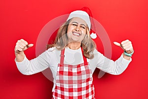 Middle age caucasian woman wearing cook apron and christmas hat very happy and excited doing winner gesture with arms raised,