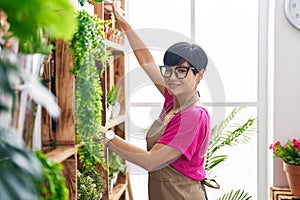 Middle age chinese woman florist smiling confident holding plant at flower shop