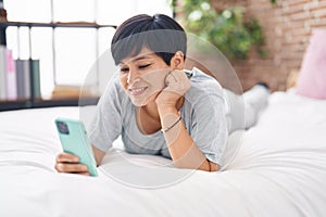 Middle age chinese woman using smartphone lying on bed at bedroom