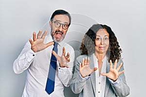 Middle age couple of hispanic woman and man wearing business office uniform afraid and terrified with fear expression stop gesture