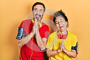 Middle age couple of hispanic woman and man wearing sportswear and arm band begging and praying with hands together with hope