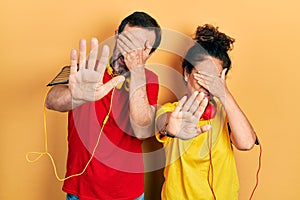 Middle age couple of hispanic woman and man wearing sportswear and arm band covering eyes with hands and doing stop gesture with