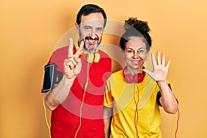 Middle age couple of hispanic woman and man wearing sportswear and arm band showing and pointing up with fingers number seven