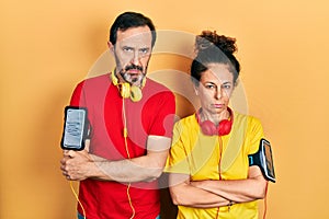 Middle age couple of hispanic woman and man wearing sportswear and arm band skeptic and nervous, disapproving expression on face