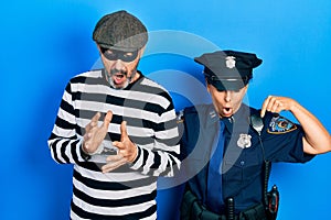 Middle age couple of hispanic woman and man wearing thief and police uniform pointing down with fingers showing advertisement,