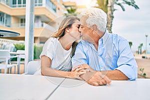 Middle age couple in love sitting at the terrace of coffee shop kissing happy and cheerful together