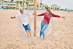 Middle age couple in love walking having fun ath the beach happy and cheerful together