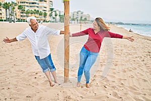 Middle age couple in love walking having fun at the beach happy and cheerful together