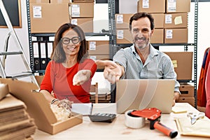 Middle age couple working at small business ecommerce smiling cheerful offering palm hand giving assistance and acceptance