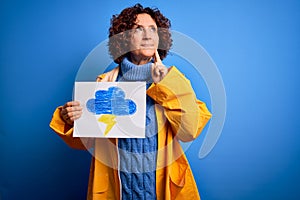 Middle age curly hair woman wearing rain coat holding banner with cloud and thunder serious face thinking about question, very