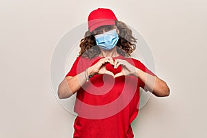 Middle age delivery woman wearing red cap and coronavirus protection mask smiling in love doing heart symbol shape with hands