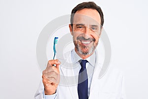 Middle age dentist man holding toothbrush standing over isolated white background with a happy face standing and smiling with a