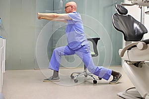 Middle age dentist stretching legs and arms.