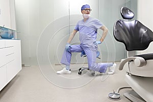 Middle age,dentist  stretching legs sitting on dental saddle