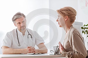 Middle age doctor and female patient at hospital office