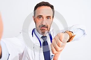 Middle age doctor man wearing stethoscope make selfie over isolated white background with angry face, negative sign showing