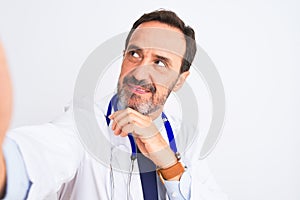 Middle age doctor man wearing stethoscope make selfie over isolated white background serious face thinking about question, very