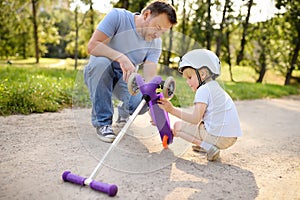 Middle age father and his toddler son watching break scooter