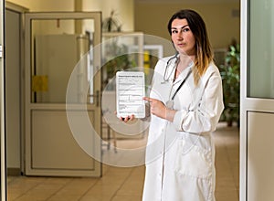 Middle age female doctor in white robe holding and pointing to tablet with Hospital Admission form