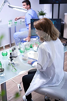 Middle age female scientist taking a sample of soil for for microscope analysis