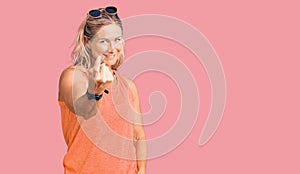 Middle age fit blonde woman wearing casual summer clothes and sunglasses beckoning come here gesture with hand inviting welcoming