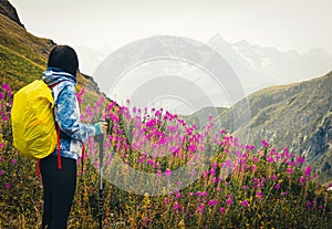 Middle-age fit sporty female hiker with nordic walk pols stand on viewpoint uphill in green hiking trail in Georgia caucasus