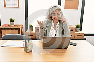 Middle age grey-haired call center agent woman smiling happy working at the office