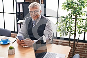 Middle age grey-haired man business worker using smartphone working at office