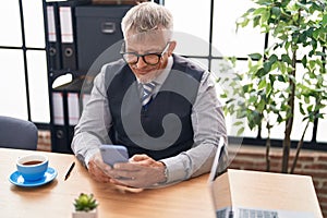 Middle age grey-haired man business worker using smartphone working at office