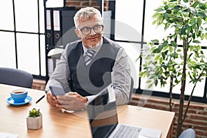 Middle age grey-haired man business worker using smartphone working at office