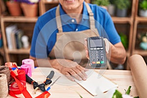 Middle age grey-haired man florist smiling confident holding data phone at florist