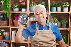 Middle age grey-haired man florist smiling confident holding data phone at florist