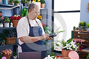 Middle age grey-haired man florist using data phone at florist