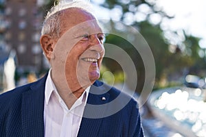 Middle age grey-haired man smiling confident looking to the side at park