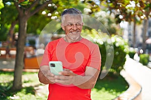 Middle age grey-haired man smiling confident using smartphone at park