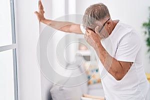 Middle age grey-haired man suffering dizzy standing at home