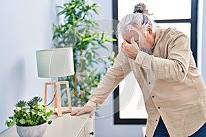 Middle age grey-haired man suffering dizzy standing at home