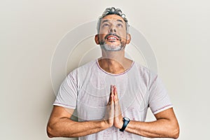 Middle age grey-haired man wearing casual clothes begging and praying with hands together with hope expression on face very
