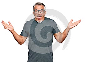 Middle age grey-haired man wearing casual clothes and glasses celebrating victory with happy smile and winner expression with